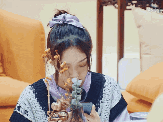 a girl with a purple bow in her hair holds a vase of flowers