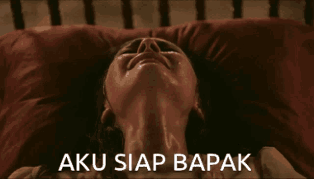 a woman is laying on a bed with the words aku siap bapak written above her
