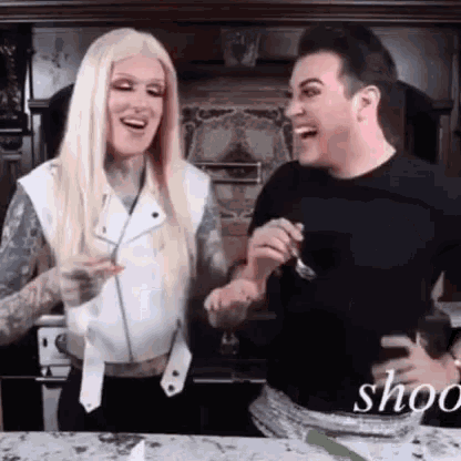 a man and a woman are laughing in a kitchen .