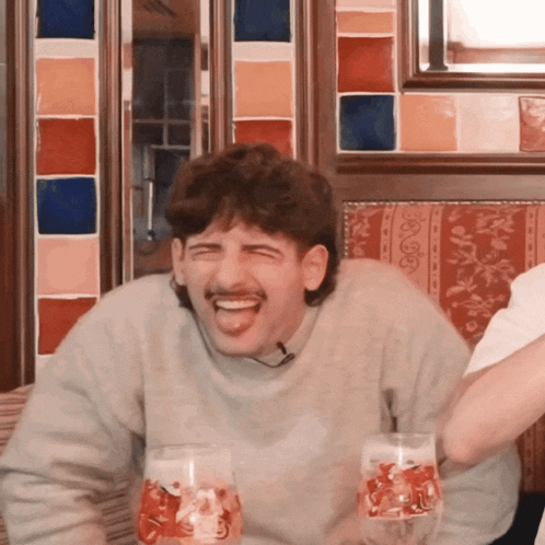 a man with a mustache is laughing while holding two glasses with santa on them