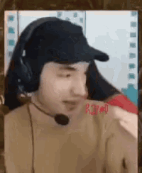 a man wearing headphones and a hat with a microphone on his neck is talking on a video call .
