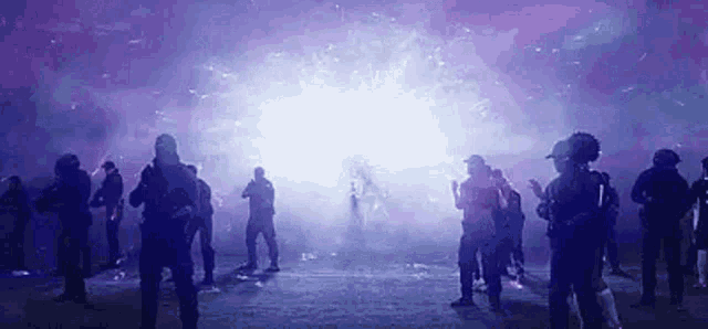 a group of people are standing in a dark room in front of a purple light .