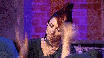 a woman with red hair is sitting on a couch with her hands outstretched .