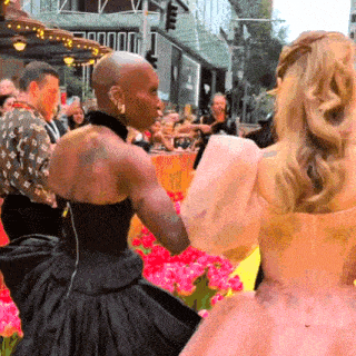 a woman in a black dress is standing next to a woman in a pink dress .
