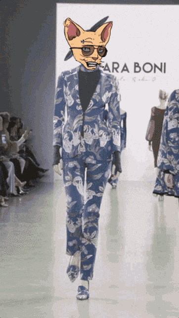 a cat wearing sunglasses walks down a runway in front of a sign that says araboni