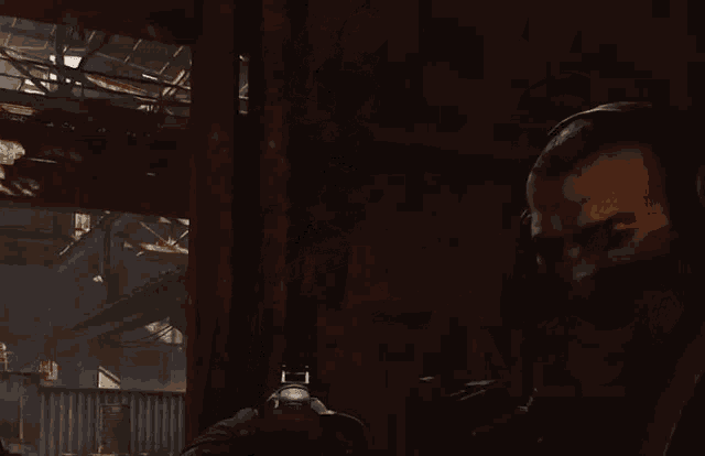 a man wearing a mask is holding a gun in a dark room .