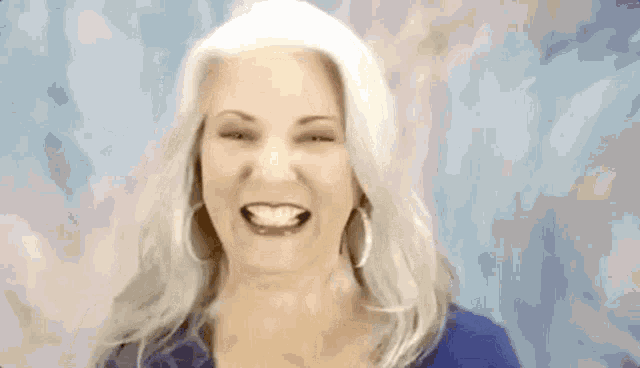 a woman with gray hair and hoop earrings is smiling with her eyes closed .