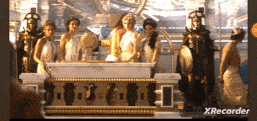a group of people standing around a table with xrecorder on the bottom right