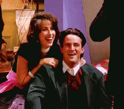 a man and woman are posing for a picture and the woman is sitting on the man 's shoulders