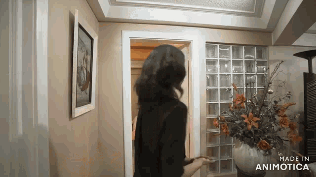 a woman is standing in a room with a vase of flowers and the words made in animotica