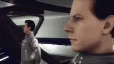 two men are standing next to each other in a room and one of them is looking at the camera .