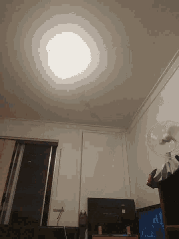 a room with a fan and a tv and a light on the wall