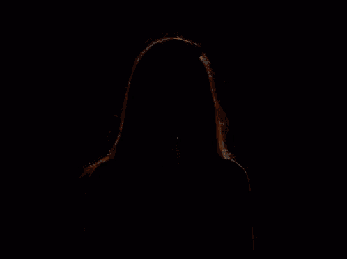 a woman is singing into a microphone in a dark room