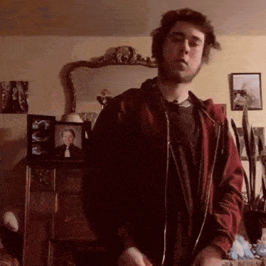 a man in a red jacket is standing in front of a mirror .