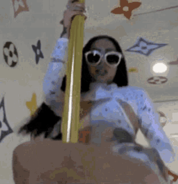 a woman wearing sunglasses stands on a pole