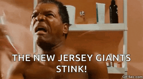 a shirtless man is crying in a bathroom with the words `` the new jersey giants stink '' .