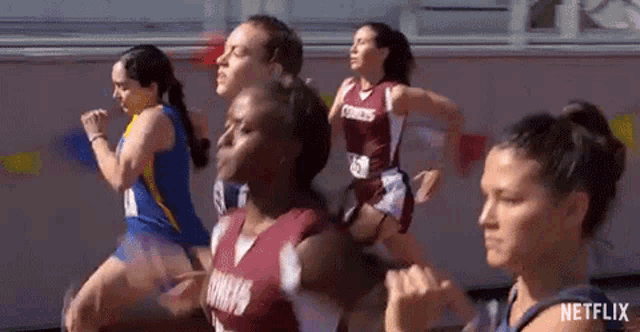 a group of female runners are running on a track .