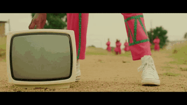 a person in pink pants is holding an old television