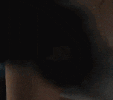 a woman with long dark hair is sitting in a dark room