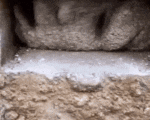 a close up of a person 's hand holding a piece of concrete on top of a pile of dirt .
