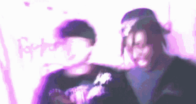 a blurry picture of two men standing next to each other in front of a purple background .