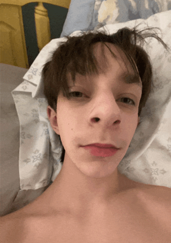 a young man laying on a bed with a louis vuitton blanket