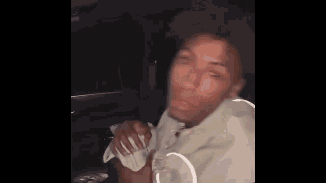 a young man is sitting in the back seat of a car holding a bunch of money .