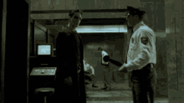 a man in a suit is talking to a police officer in a dark room