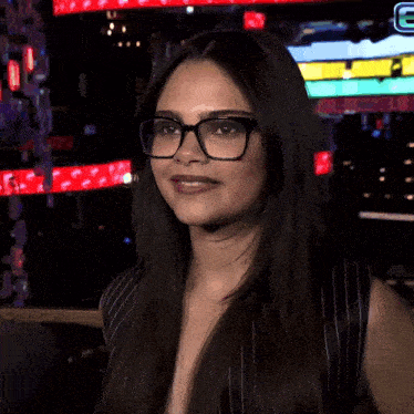 a woman wearing glasses stands in front of a sign that has the letter e on it