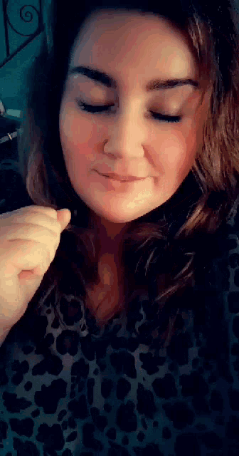 a close up of a woman 's face with her eyes closed and a leopard print shirt .