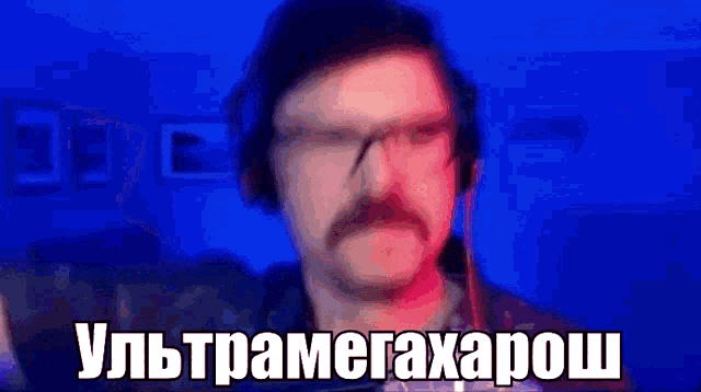 a man with glasses and a mustache is wearing headphones and says in russian .