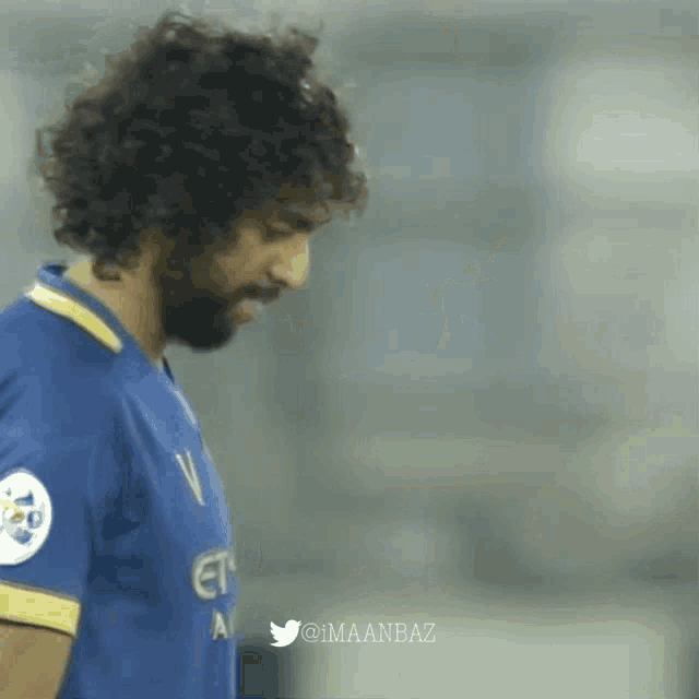 a man with curly hair and a beard is wearing a blue etisalat jersey