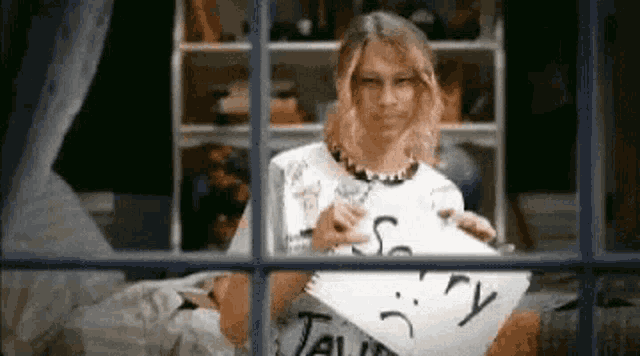 a girl is holding a piece of paper that says sorry .