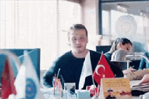 a man is sitting at a desk with flags on it