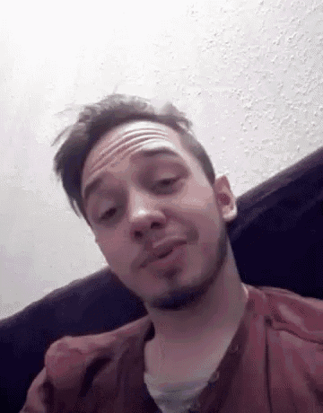 a man with a beard is making a funny face while sitting on a couch .