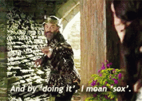 a man with a beard is standing in front of a stone wall and says and by doing it i mean sex