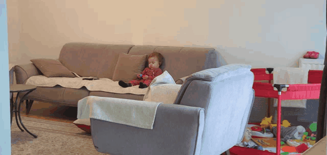 a baby is sitting on a couch with a remote control