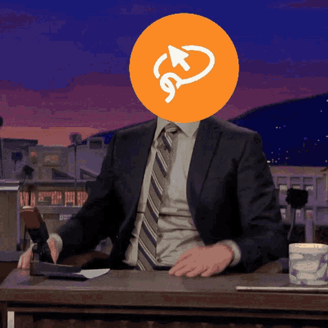 a man in a suit sits at a desk with an orange circle on his head with an arrow pointing to the right
