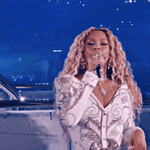 a woman singing into a microphone wearing a white shirt