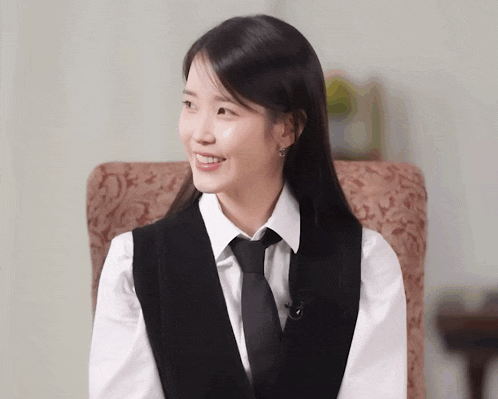a woman wearing a vest and tie is smiling