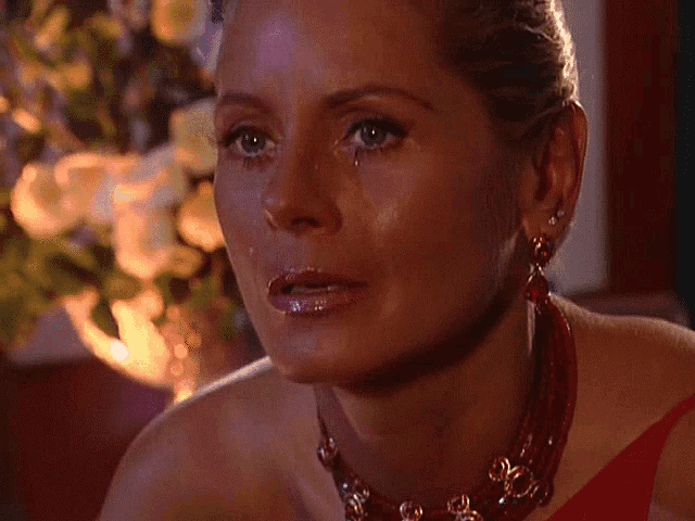 a woman wearing a red necklace and earrings looks at the camera