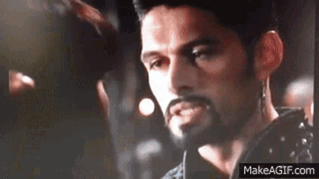 a close up of a man with a beard and earring .