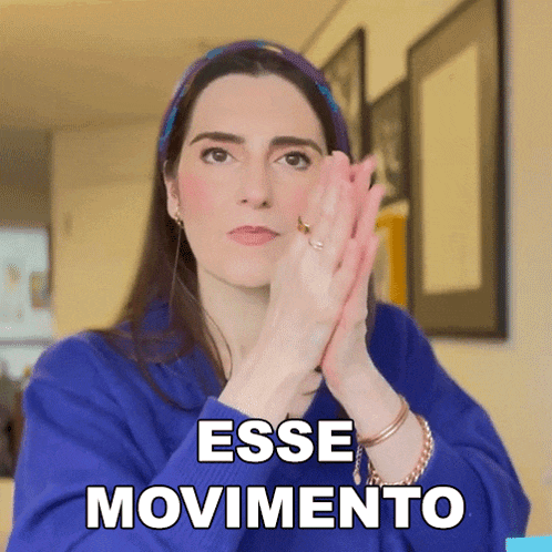 a woman in a blue sweater is clapping her hands and the words esse movimento are visible