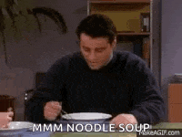 a man is sitting at a table eating noodles with a fork and knife .