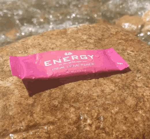 a pink energy bar with pink lemonade flavor sits on a rock