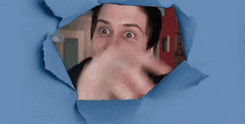 a man is looking through a hole in a blue paper