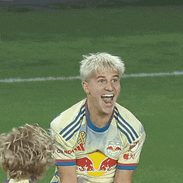 a man wearing a yellow and blue red bull jersey is smiling