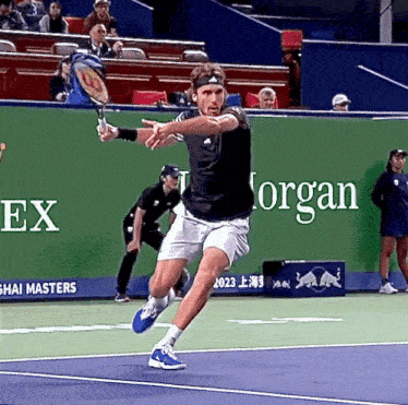 a man is swinging a tennis racquet on a tennis court in front of a green wall with the word organ on it