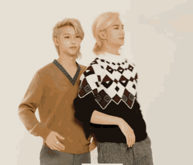 two men are standing next to each other and one is wearing a sweater with a checkered pattern