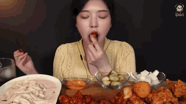 a woman is sitting at a table eating fried chicken and noodles .